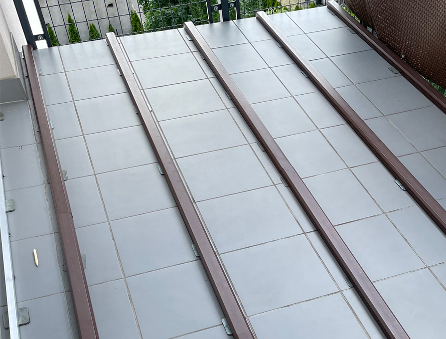 Montaż deski kompozytowej na balkonie w Warszawie – legary kompozytowe ułożone na istniejących płytkach